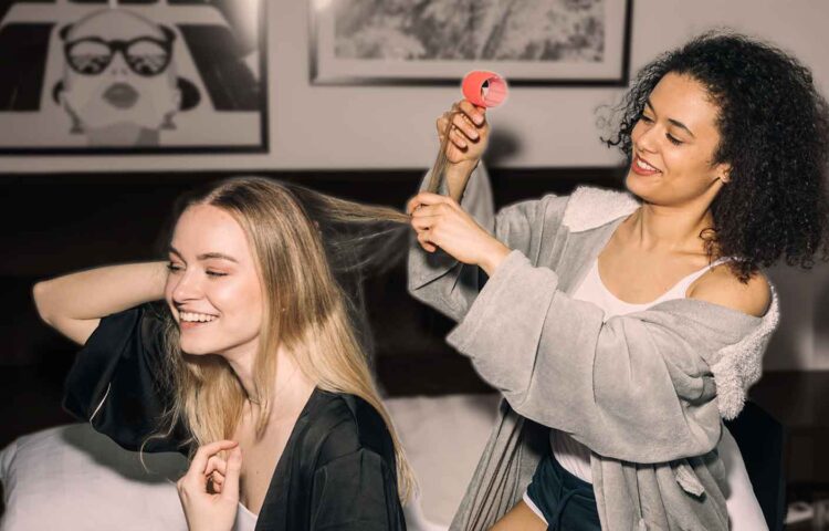 Two friends help each other install hair rollers.